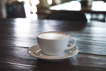 Closeup image of a white cups of hot coffee on vintage wooden table in cafe