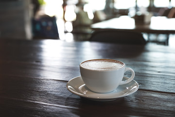 Closeup image of a white cups of hot coffee on vintage wooden table in cafe