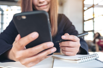 Closeup image of a beautiful asian woman holding , using and looking at smart phone while working in office