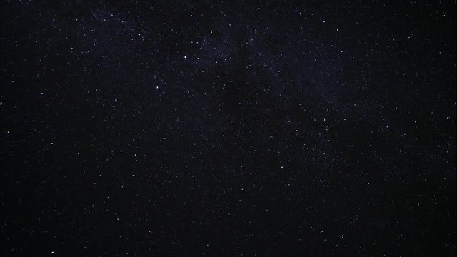 Starry night sky. Twinkling stars in the dark night sky. Light clouds drifting in the night sky. Time lapse