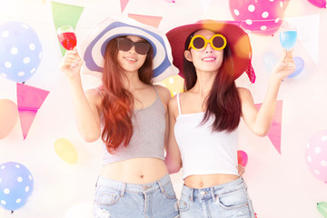 Young beautiful women celebrate holiday party and dancing.Best friends wearing casual shorts and T-shirt,having fun,drinking alcohol cocktails.Pastel tone.