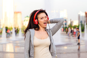 Girl listening to music streaming with headphones and winking.