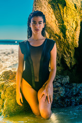 Portrait of latino woman with curly hair, black swimsuit at beach
