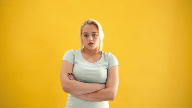 Sad blond caucasian plus size model in a bad mood at yellow background slow motion