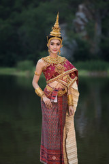 Young asian girl in thai traditional dress and the river green garden background at evening time 