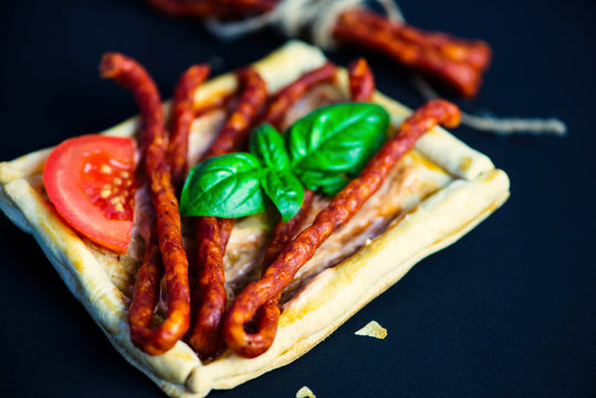 puff pastry sandwich with sausages and spices on a wooden board