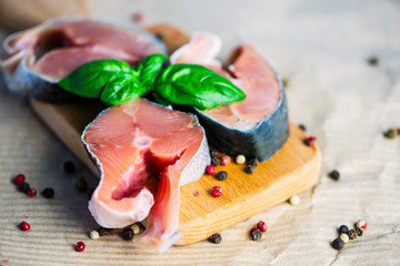 raw pieces of salmon and spices on a wooden board on paper