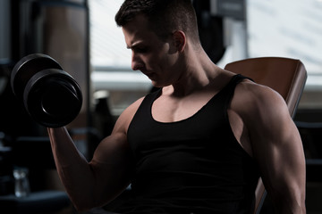 Bodybuilder Exercising Biceps With Dumbbells