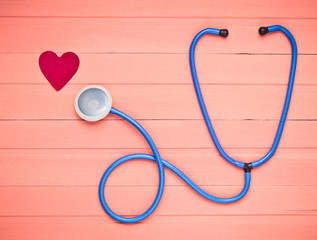 Stethoscope and heart on pastel pink wooden table. Cardiology equipment for diagnosing...
