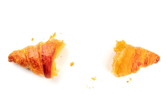 An overhead photo of a croissant torn in two halves to see the texture, shot from above on a white background with copy space