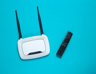 Wi fi router, tv remote on blue background. Top view.