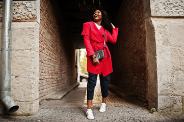 Fototapeta na wymiar Stylish african american woman in red coat posed at tonel outdoor.
