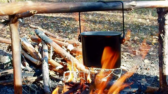 Camping pot on the bonfire. Extreme tourism in the wild forest.