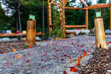 Wooden structure with various colors of silk lantern boats displayed and flower petals scattered on the floor all around - 1/2 - Wide angle picture taken outside in northern Quebec, Canada