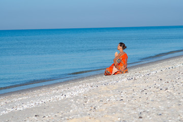 Fototapeta na wymiar Woman relaxes and meditates on a deserted beach