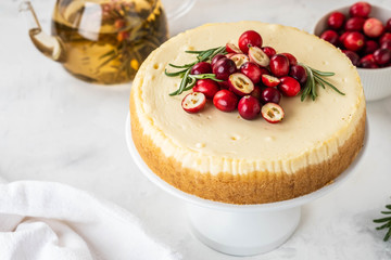 Classic New York Cheesecake with cranberry, rosemary and tea on White Concrete Background, copy spase. Tea and Cheesecake