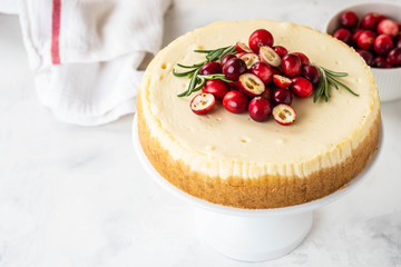 Classic New York Cheesecake with cranberry, rosemary and tea on White Concrete Background, copy spase. Tea and Cheesecake