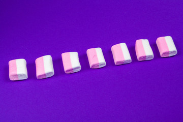 marshmallow laid out on violet paper background.