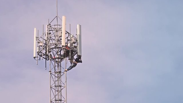 Professional services for smart phone wireless network.
Unidentified technicians working on 4G antenna tower for routine maintenance with safety equipment at sunset,4K video.