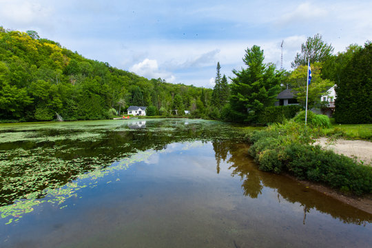 Calm lake with water lilies and chalets around - Wide angle picture taken in Quebec, Canada