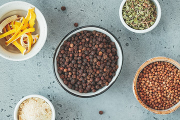 Different spices in bowls on a grey textured background. Top view.
