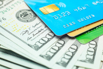 Credit cards and stack of banknotes 100 dollars in cash. Electronic money with a security chip for payment in the store. closeup