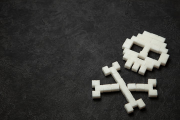 Skull from white sugar cubes on black background. Sugar kills and lot of fast ulevodov harmful to the body. Diabetes mellitus to death. Copy space for text