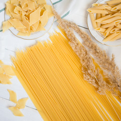 varieties of pasta on a white wooden table, spaghetti, Penne, maltagliati, local cuisine