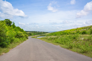 Landscape Scenic road travel on empty highway near a large reservoir with sky and clouds background.