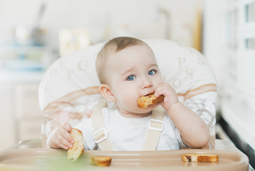 Baby girl eating cracker with raisins in a chair