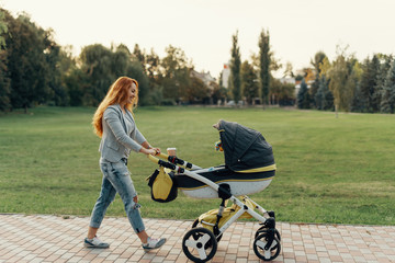 Mother enjoying walk carrying her little child in his baby troll
