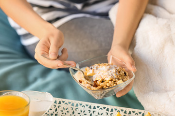 Young woman having delicious breakfast on bed, closeup