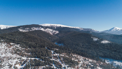 Aerial view of the mountains. Bukovel. Carpathians. Snow. Winter. Forest. Trees. Day.