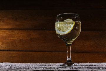 Alcohol is poured into a glass in which a slice of lemon with bubbles is lying