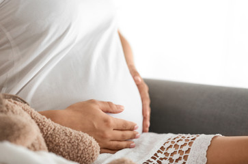 Beautiful pregnant woman sitting in armchair at home, closeup