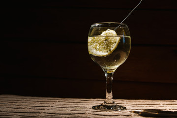 Alcohol is poured into a glass in which a slice of lemon with bubbles is lying