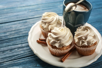 Tasty cupcakes with cup of coffee on wooden table