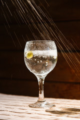 Champagne is poured into a glass, at the bottom of which is an olive