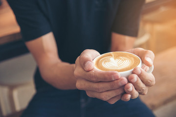 Late art a cup of coffee on barista hands. young hipster love coffee