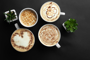 Cups with tasty aromatic coffee on black background, flat lay