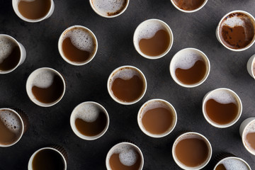 Many plastic cups with tasty aromatic coffee on dark background, flat lay
