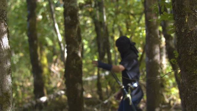 Girl in a Ninja Outfit Walking through the Trees in Slow Motion