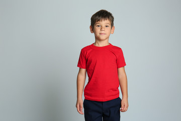 Cute little boy in t-shirt on grey background © Pixel-Shot