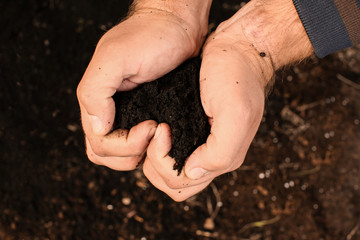 Man holding black soil outdoors