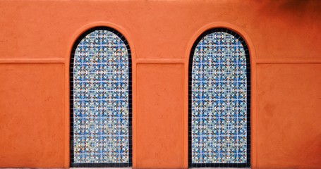 orange wall colour facade with blue colour closed door in the center of large empty orange wall texture background space.