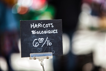 Chalk sign selling organic beans for 6 dollars a pound in a french canadian farmer's market under the name haricots biologiques - Closeup picture on the sign mounted on a clip