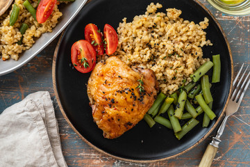 Grilled chicken thighs with bulgur, asparagus beans and tomatoes. Delicious lunch. Copy space.