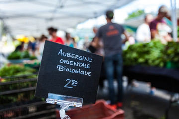 Chalk sign selling organic asian eggplant in a french canadian farmer's market under the name aubergine orientale biologique - Closeup picture on the sign mounted on a clip