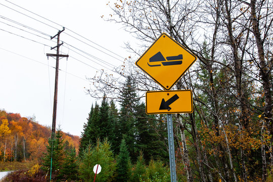 Snowmobile track to the left yellow road sign - 1/3 - Picture taken in Quebec, Canada, while autumn colors were very present. Perspective from the side of the road