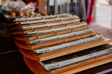 Multiple menu folders in a cafe or bar. Decorated on a wooden substrate with metal rings